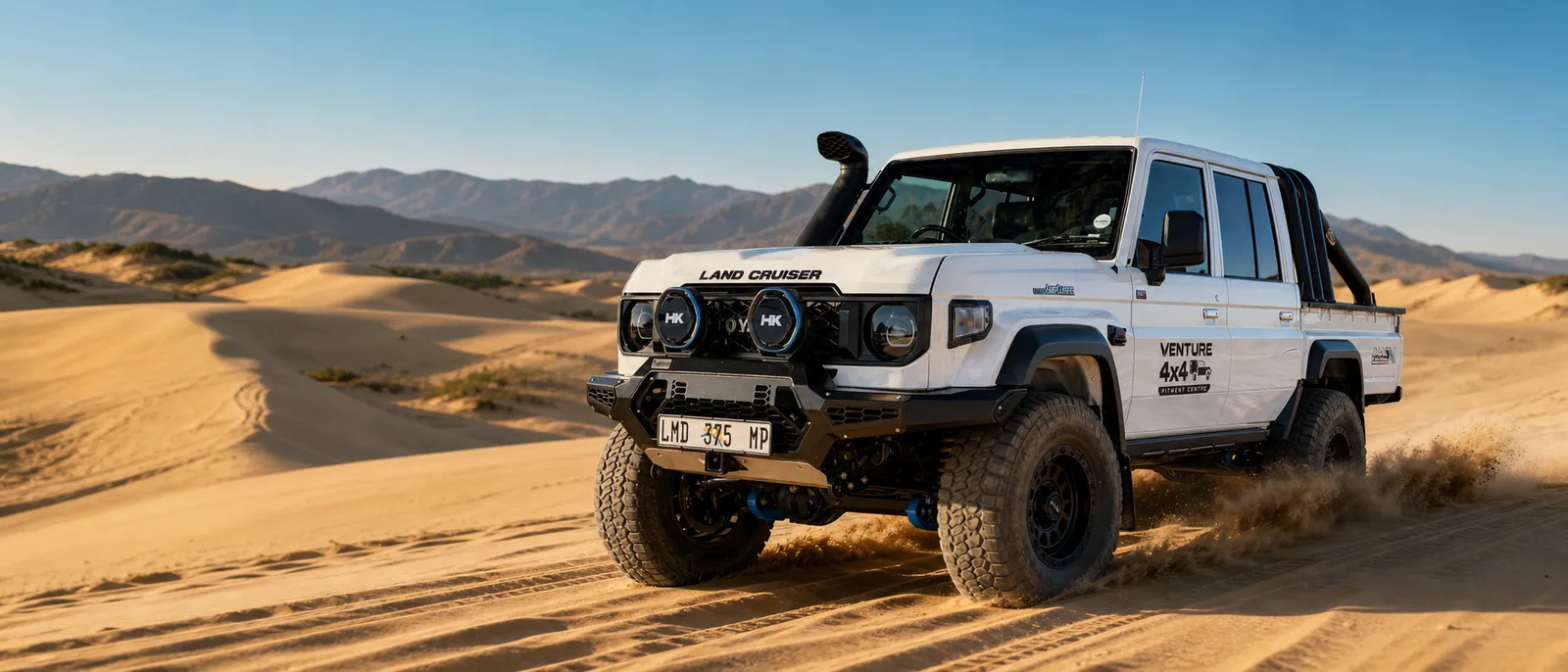 White Toyota Land Cruiser 79 fitted by Venture 4x4 driving through dunes